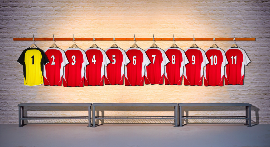 Row of Red and Blue Football Shirts 1-11 hanging on locker room wall
